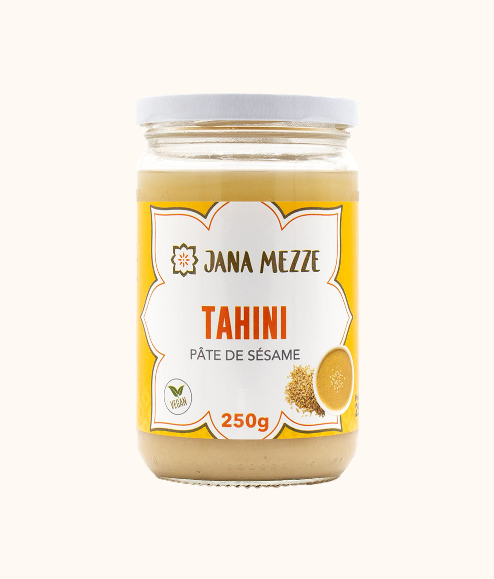 A jar of Jana Mezze brand tahini, 250g, with a label showing the product name and an image of a lemon, indicating it is a creamy sesame seed paste.